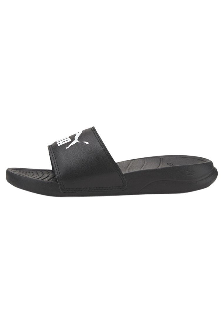 Black slide sandal with a wide strap, textured footbed, and a white logo. Material appears smooth, with a low-profile design and rubber sole.