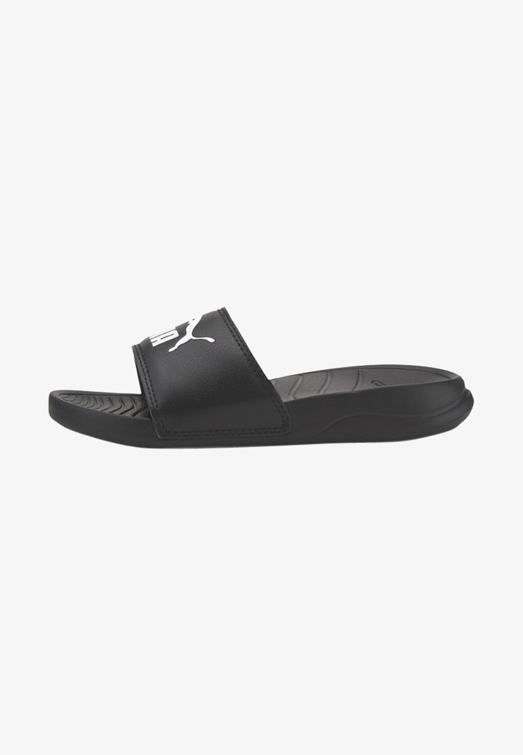 Black slide sandal with a wide strap, textured footbed, and a white logo. Material appears smooth, with a low-profile design and rubber sole.