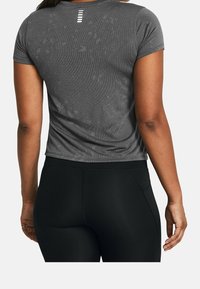 Šedé sportovní tričko s krátkým rukávem, texturovaná tkanina a jemné vzory, kombinované s černými legínami s vysokým pasem.