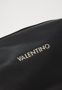 Zwarte leren tas met een gladde textuur en een gouden "VALENTINO" logo, gekenmerkt door een slank, rechthoekig ontwerp.