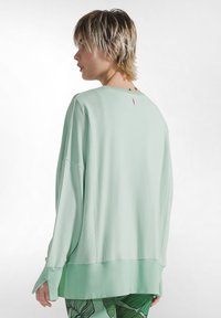 Vaaleanmintunvihreä ylisuurikokoinen svetari, jossa pitkät hihat, pyöreä pääntie ja ommellut helmareunukset. Kauluksessa näkyvä takalappu. Pehmeä kangaspinta.