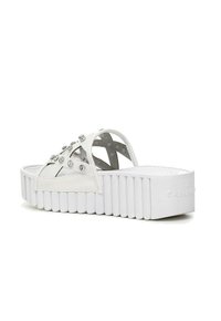 I sandali platform bianchi presentano una suola spessa e rigata, borchie decorative in argento e un design con fasce incrociate e motivi a intaglio.