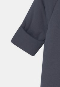 Chemise bleu marine à manches courtes avec un revers et un tissu lisse, légèrement texturé. Pas de motifs ni d'accents visibles.