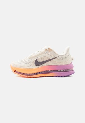 Fehér Nike Air Max sportcipő fekete Swoosh logóval és narancssárga, rózsaszín és lila árnyalatú színátmenetes talppal, oldalnézet világos háttér előtt.
