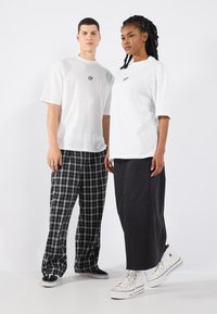 Bílé oversized trička, černé a šedé kostkované kalhoty, dlouhá tmavá džínová sukně a bílé tenisky. Jednoduché barvy s jednoduchými vzory.