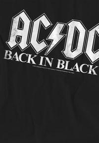 Black t-shirt featuring "AC/DC" in bold, distressed white lettering, with a lightning bolt and "BACK IN BLACK" below in a slightly smaller font.