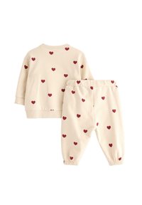 Ljusbeige loungekläder med röda hjärt-mönster. Inkluderar en långärmad topp med ribbade ärmar och matchande byxor med elastisk midja.