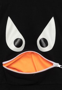 Felpa nera con grandi appliqué bianchi a forma di occhio, con una tasca frontale con zip foderata in tessuto arancione brillante. Presenta dettagli testurizzati.