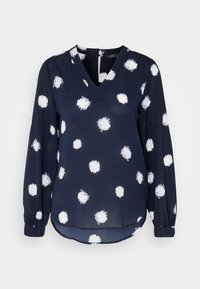 Blusa de manga larga azul marino con lunares blancos irregulares, escote en V, puños elásticos y dobladillo ligeramente curvado.