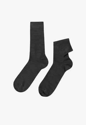 Dunkelgraue Socken in unterschiedlichen Längen, mit einer weichen Textur und glattem Strickdesign. Der längere Socke hat eine klassische Crew-Höhe, während der kürzere knöchellang ist.