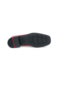 Suola della scarpa con una base in gomma nera, battistrada testurizzato per una migliore aderenza e un accento rosso vicino al tallone. Forma piatta e rettangolare.