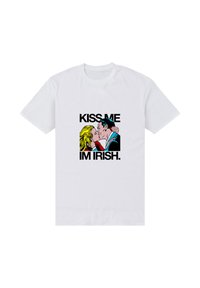 Bílé bavlněné tričko s grafickým potiskem páru líbajícího se. Text zní "KISS ME I’M IRISH" tučnými černými písmeny.