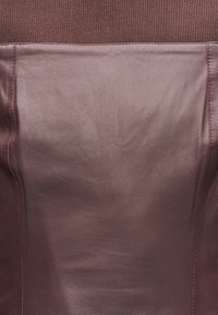 Ρουχιστικό από δέρμα μπορντό με ραβδωτό επάνω τμήμα. Διαθέτει λείο υφή και ορατή ραφή κατά μήκος των ραφών.