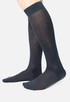 Schwarze knielange Socken aus einem glatten, dünnen Stoff, mit einem gerippten oberen Rand und nahtlosem Zehendesign.