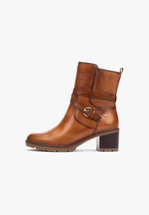 Bottine en cuir marron, avec un bout carré, fermeture éclair latérale et détail de boucle. Présente un talon en bois et une semelle extérieure en caoutchouc texturé.