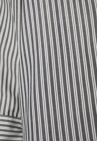 Gros plan sur un tissu à rayures verticales noirs et blancs avec une texture de tissage visible.