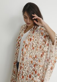 Kwiatowy kimono, lekkie tkaniny z pomarańczowymi, fioletowymi i zielonymi kwiatami na kremowym tle. Otwarty przód z szerokimi rękawami.