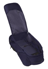 Mochila de tela azul marino con parte superior abierta, que cuenta con un bolsillo de malla y correas interiores. Textura suave, forma estructurada y clips laterales ajustables.