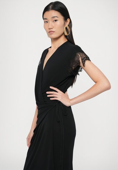 Čierne zavinovacie šaty s čipkovaným lemovaním na rukávoch, hlbokým výstrihom do V a bočným viazaním na nastaviteľné prispôsobenie. Hladká, jemne prúdiaca látka.