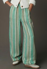 Pantalon large léger vert menthe avec des rayures verticales crème et marron. Comprend une taille élastique et des poches latérales.