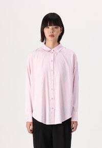 Camicia a maniche lunghe con bottoni di colore rosa chiaro a strisce verticali bianche. Presenta un colletto a punta e maniche con polsini. Tessuto dalla trama liscia.