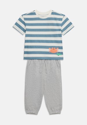 Κοντομάνικο μπλε και άσπρο ριγέ πουκάμισο με γραφικό καβούρι και ψάρι, συνδυασμένο με ανοιχτό γκρι παντελόνι με ελαστική μέση και τσέπες.