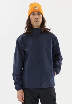 Marinsblå vattentät jacka med hög krage, frontdragkedja och elastiska ärmslut; tillsammans med en orange mössa med logotypapplikation.