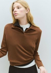 Brown long-sleeve top with a collared neckline, layered over a white undershirt. Smooth texture, relaxed fit, and ribbed hem details.