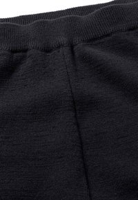 Schwarzer Strickstoff mit einem gerippten Taillenbund, der eine glatte Textur und minimale Nahtdetails aufweist. Die Nahaufnahme zeigt Weichheit und Dehnbarkeit.