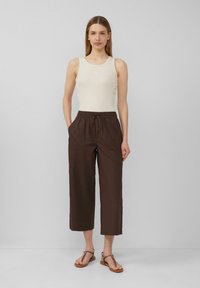 Lichtbeige geribde tanktop gecombineerd met bruine cropped broeken met een trekkoord in de taille, zijzakken en een ontspannen pasvorm.