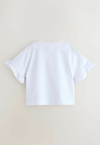 Valkoinen lyhythihainen pyöreäkauluksinen crop-top, jossa on röyhelöhihat. Valmistettu sileästä puuvillasta, yksivärinen malli.