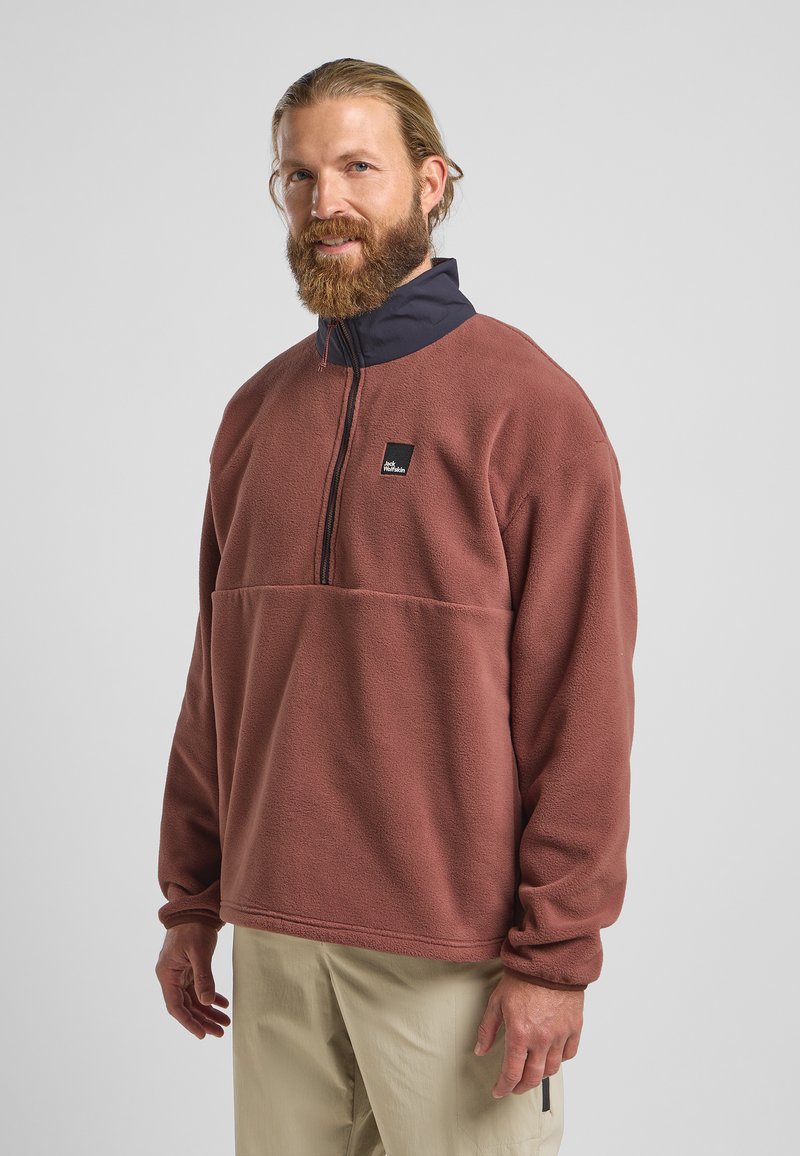 Pullover en polaire couleur rouille avec un col marine, doté d'un design à demi-fermeture éclair et d'une poche poitrine avec un logo. Texture douce et coupe décontractée.