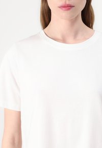 Witte t-shirt met korte mouwen en een ronde hals. De stof lijkt glad en zacht met een eenvoudig ontwerp en zonder zichtbare patronen of accenten.