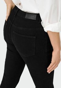 Mustadest denimist teksad, millel on sile tekstuur, slim fit ning nahast silt "ONLY" vöökohal. Sisaldab tagakotte.