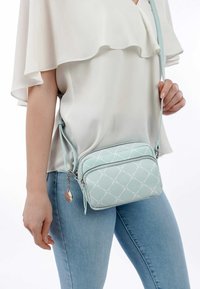 Borsa a tracolla in faux leather azzurro chiaro con un motivo a diamante, zip argentata e una tracolla regolabile, dotata di un charm decorativo.
