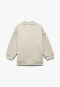 Sudadera de color beige claro con cuello alto, hombros caídos y puños acanalados. Textura suave y corte relajado.