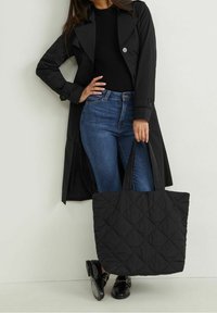 Czarna pikowana torba na ramię z podwójnymi uchwytami, ozdobiona wzorem diamentowym. Nosić z ciemnymi dżinsami i czarnym swetrem, w połączeniu z czarnym płaszczem trench.