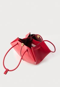 Borsa a mano in pelle rossa con chiusura dorata, apertura superiore che mostra una tasca interna e un piccolo oggetto rettangolare all'interno.