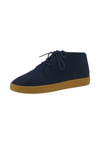 Botines de ante azul marino con textura suave, diseño con cordones y suela de goma marrón. Punta redondeada y silueta minimalista.