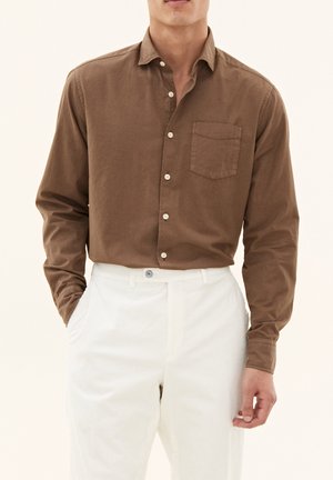 Bruine overhemdd met een zak, lange mouwen en een relaxte pasvorm, gecombineerd met lichtgekleurde corduroy broek.