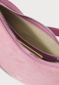 Roze suède handtas met een ritssluiting en accenten van gestructureerd leer. De binnenkant heeft een gladde voering in een lichtere tint roze.