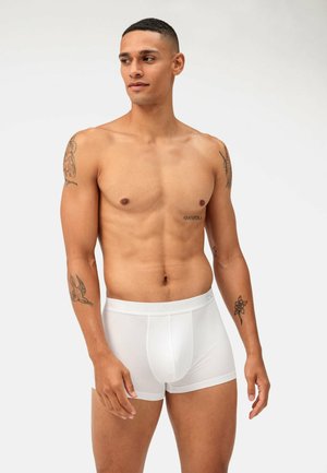 Weiße Baumwoll-Boxershorts mit fitter Passform und einem weichen elastischen Bund. Hautfarbe von der Taille aufwärts sichtbar, mit Tattoos an beiden Armen.