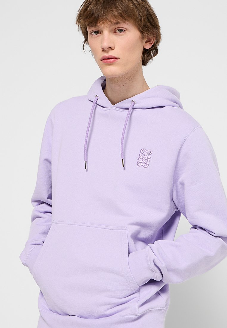 Lavender Kapuzenpullover aus weichem Stoff, mit einer Kängurutasche, verstellbarem Kapuzenzug und einem dezenten gestickten Logo in der Mitte.