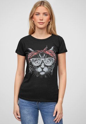 Black cotton t-shirt featuring a cat illustration with glasses and a red polka dot headband. The design is bold and graphic, set against a plain background.