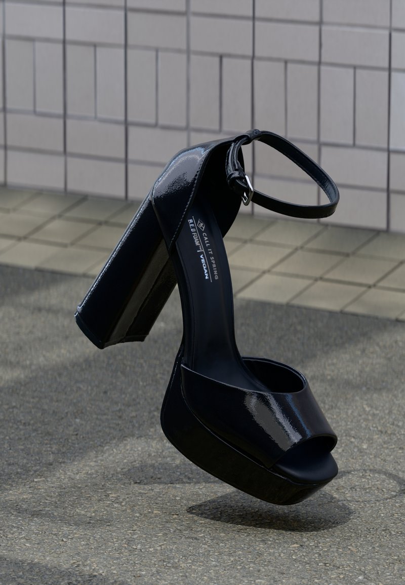 Μαύρα πέδιλα από πατέντα δέρμα με ψηλό τακούνι και πλατφόρμα, ανοιχτή μύτη, λουράκι στον αστράγα λο και χοντρό τακούνι. Λευκή, γυαλιστερή επιφάνεια.