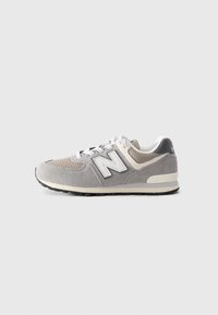 Baskets New Balance grises et beiges avec des lacets blancs et un tissu texturé, vues de côté sur un fond clair uni.
