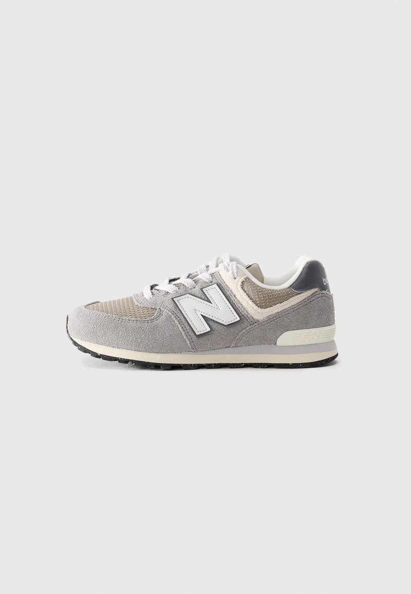 Baskets New Balance grises et beiges avec des lacets blancs et un tissu texturé, vues de côté sur un fond clair uni.