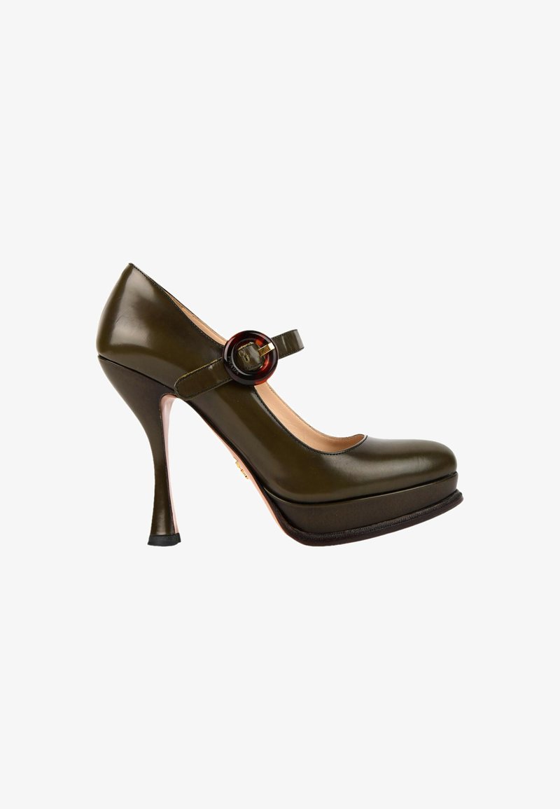 Chaussure Mary Jane à talons hauts vert olive foncé avec bout arrondi, semelle plateforme et bride à boucle circulaire sur fond blanc.
