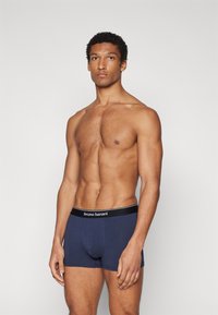 Navy boxer briefs with a black elastic waistband featuring "bruno banani" in white letters. Smooth texture and fitted design.