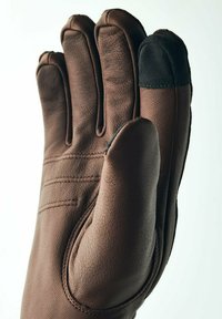 Brun læderhandske med tre hovedfingre, en sort detalje på fingerspidsen og synlige syninger langs håndfladen og bagsiden. Glat tekstur.